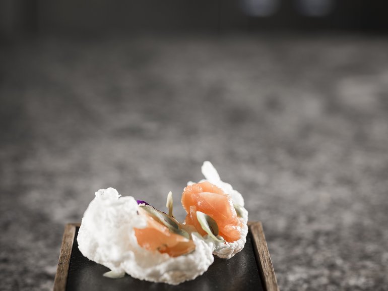 Knusprige Reiscracker mit Lachs und Kräuterdip auf schwarzem Teller