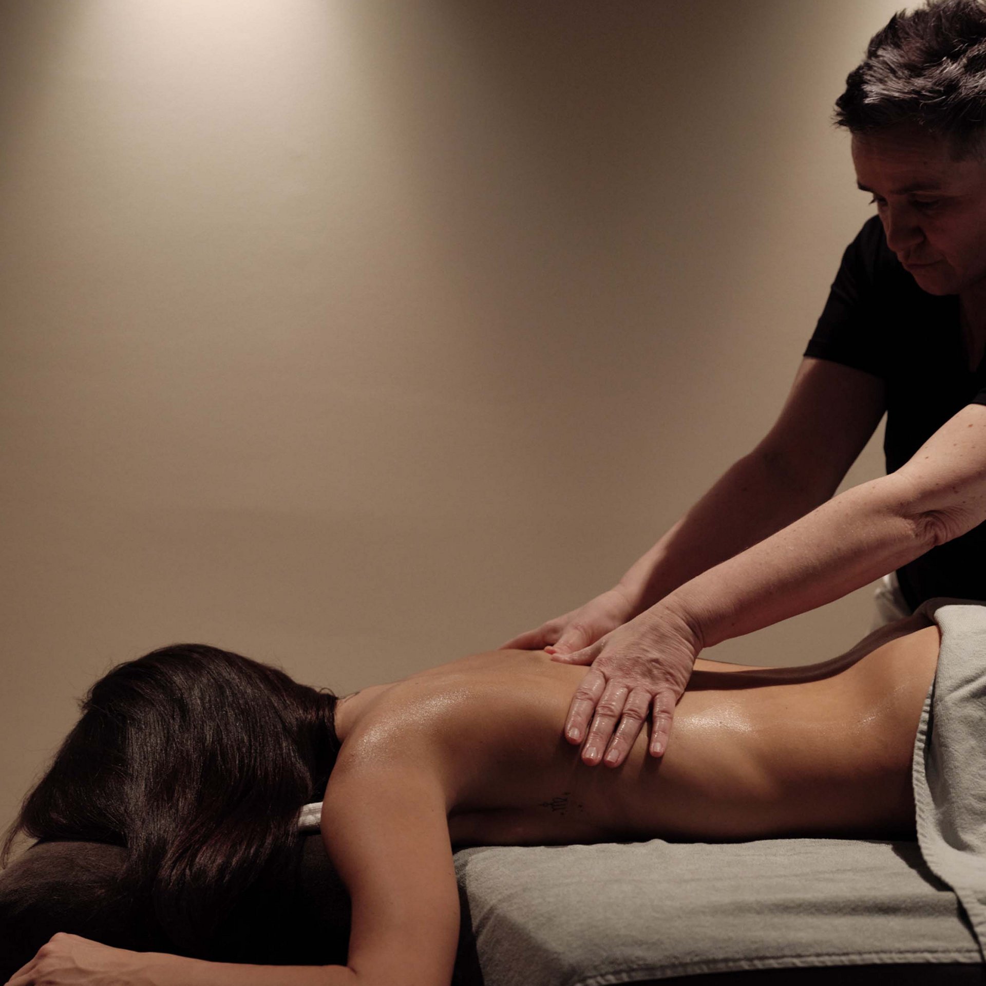 Person erhält Rückenmassage auf Massagetisch in entspannter Umgebung