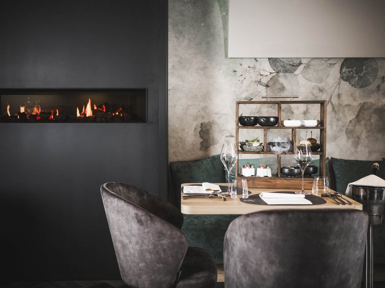 Eines der schönsten Familiehotels in Dorf Tirol Gemütlicher Esstisch mit Speisenregal neben modernem Kamin