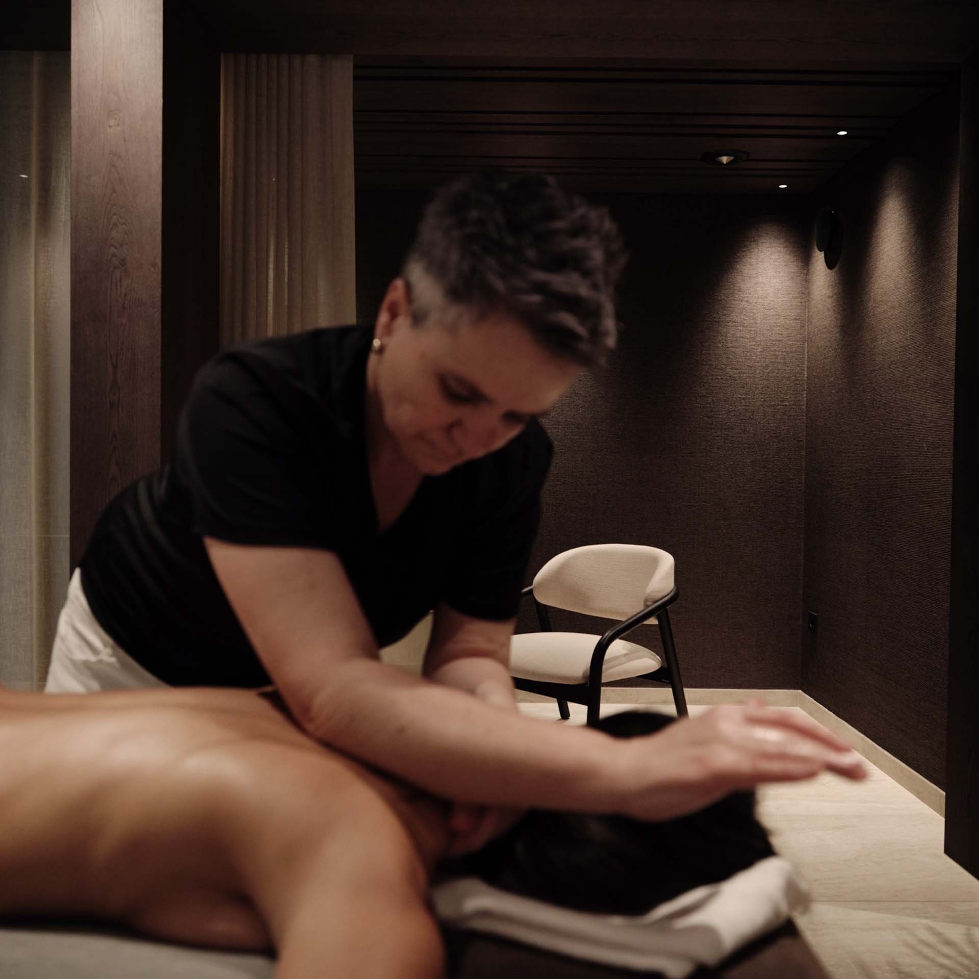 Frau gibt Rückenmassage in einem ruhigen Massageraumm