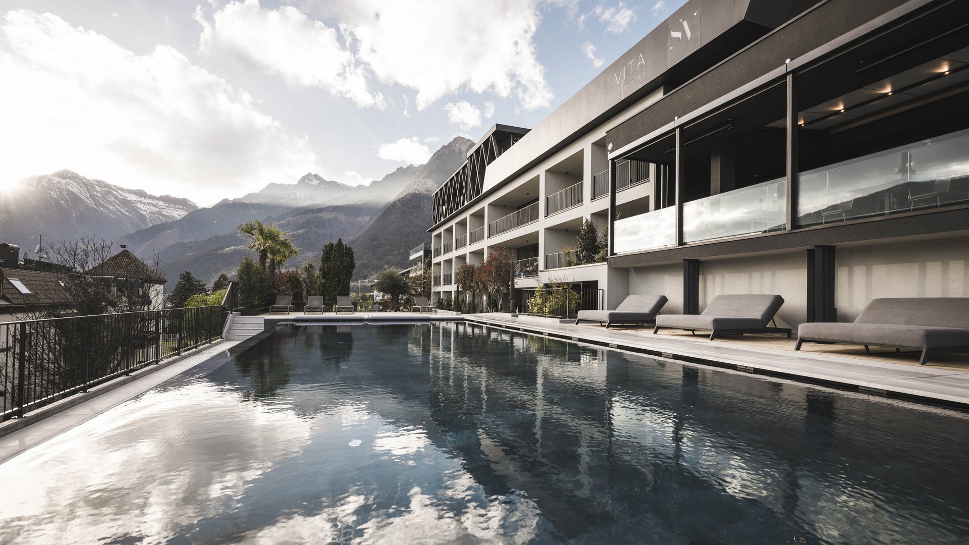 Sky Pool & Garden Pool in Dorf Tirol – Ihr Sprung ins Glück | SomVita Suites Moderner Pool mit Bergblick und Liegestühlen neben einem Hotel