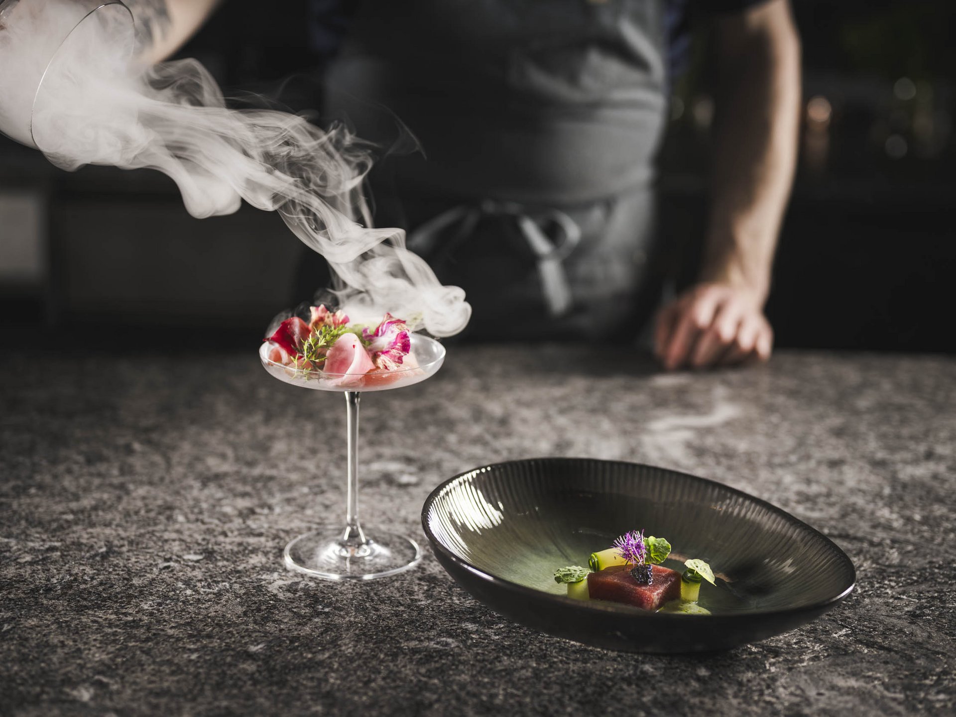 Dorf Tirol: accommodation with style and good food Smoke poured into a cocktail with flowers on a stone surface