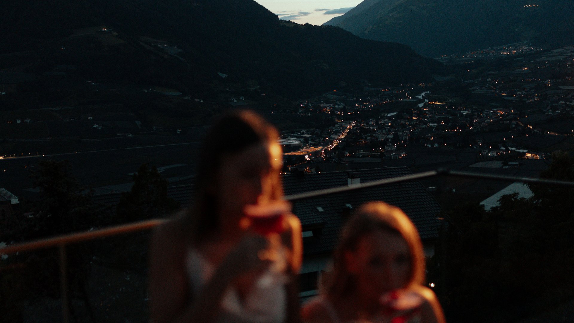 Terrasse in der Abenddämmerung, Gäste trinken Getränke, Berge im Hintergrund