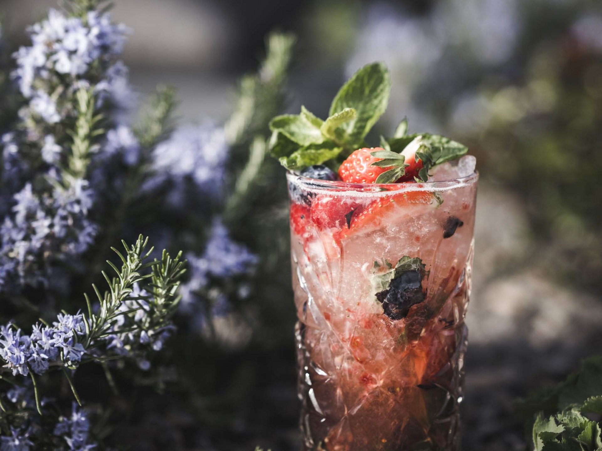 Cocktail rinfrescante ai frutti di bosco con menta davanti a fiori viola