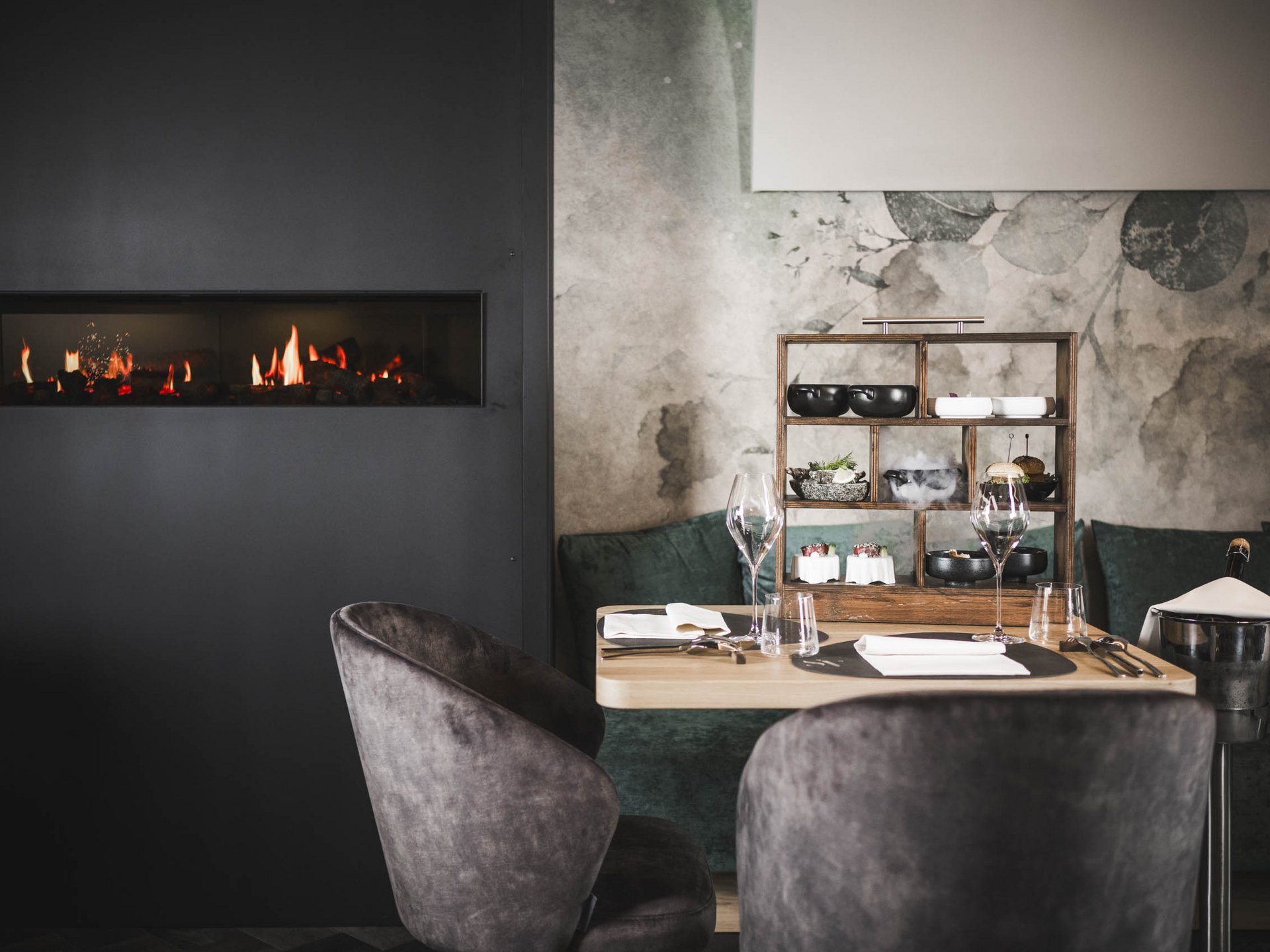 Dorf Tirol: accommodation with style and good food Cozy table with food beside modern fireplace in elegant restaurant