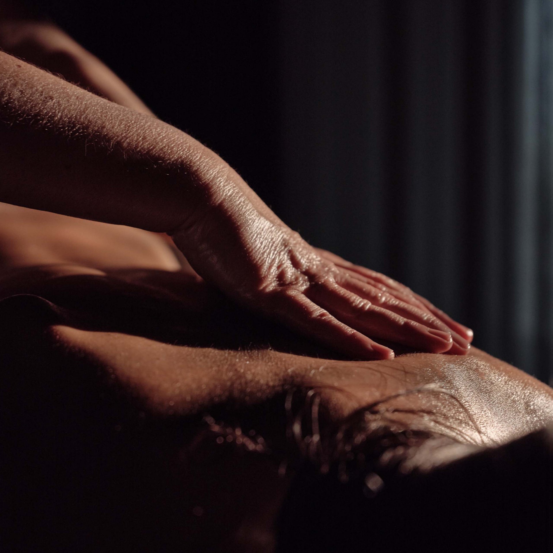 Hand massiert den Rücken einer Person in gedämpftem Licht